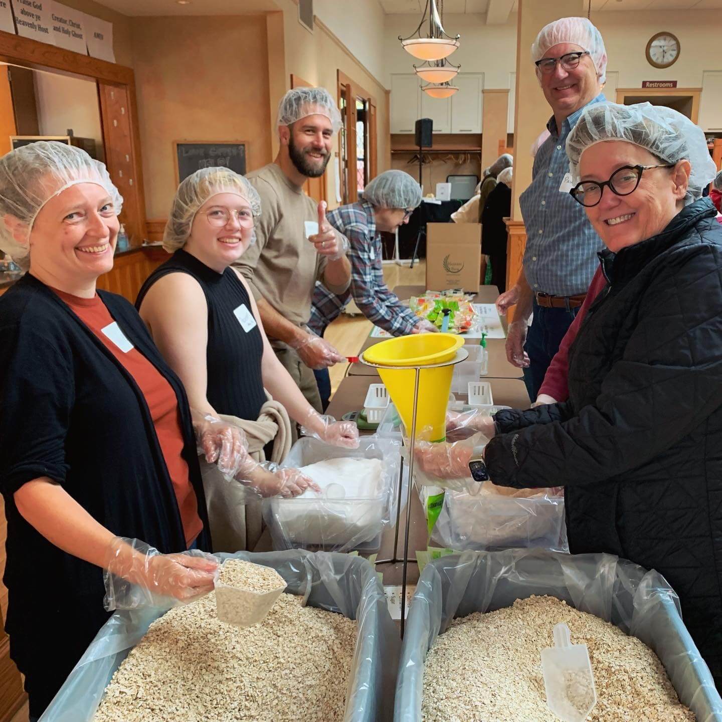 A group of smiling people packing food for a food shelf