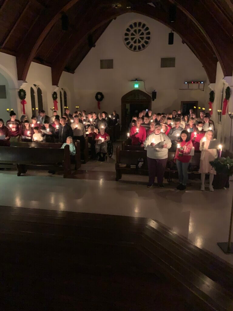 Parishioners holding lite candles in sanctuary on Christmas Eve