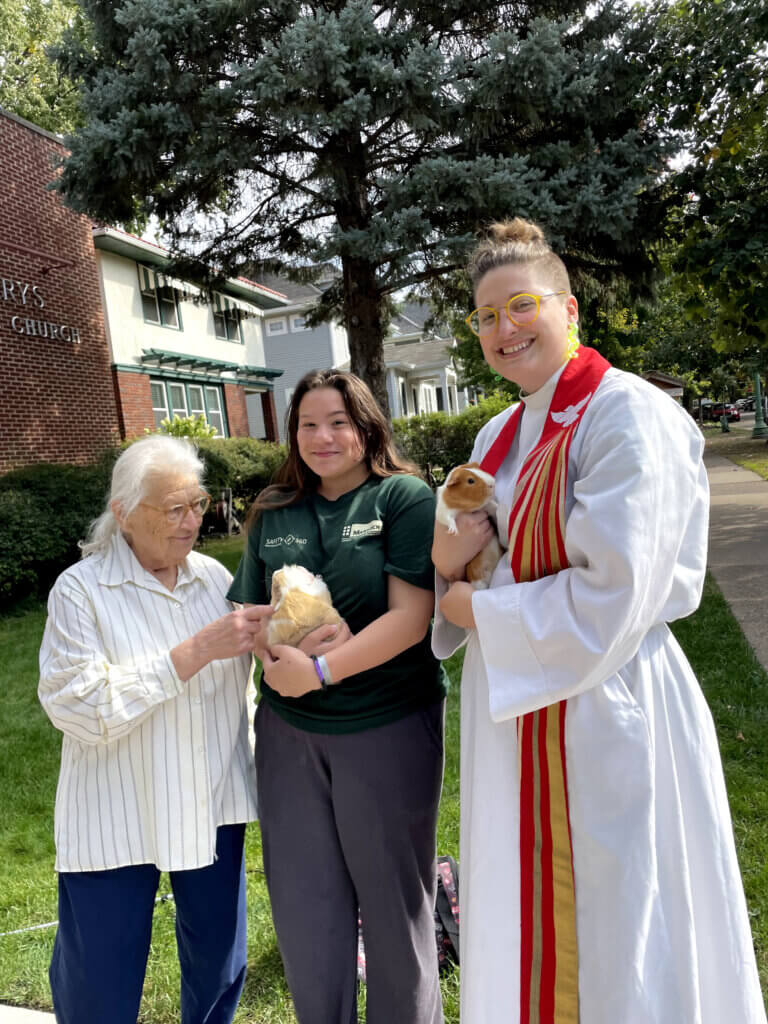 Rev Lindsey with two women parishioners holding guinea pigs outside St Mary's
