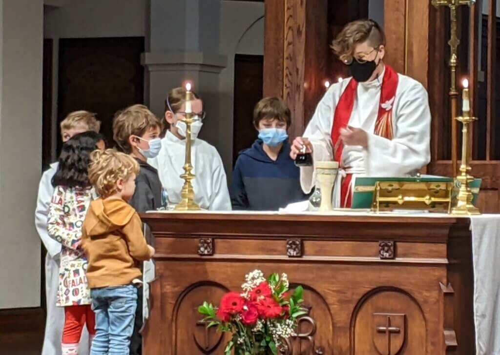 Rev Lindsey with children gathered around the altar during Eucharist